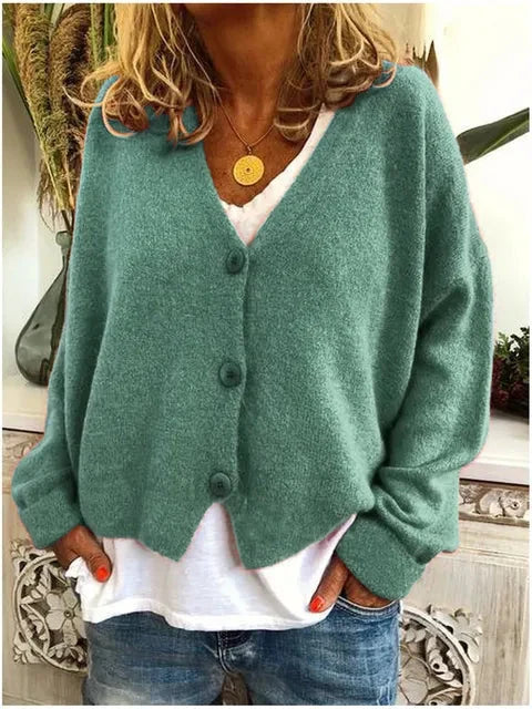 Anna draagt een groen Dames Cardigan Vest met V-hals en Knopen over een wit shirt en jeans
