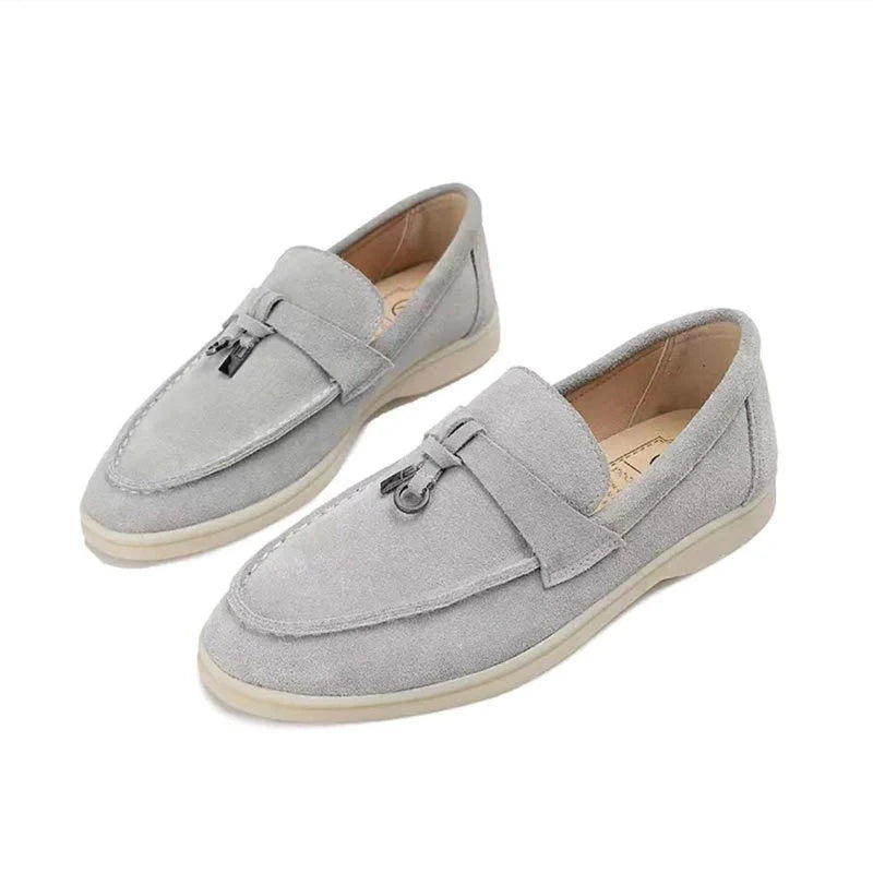 Detail bovenaanzicht van zwarte suède loafers met decoratief kwastje en contrastzool
