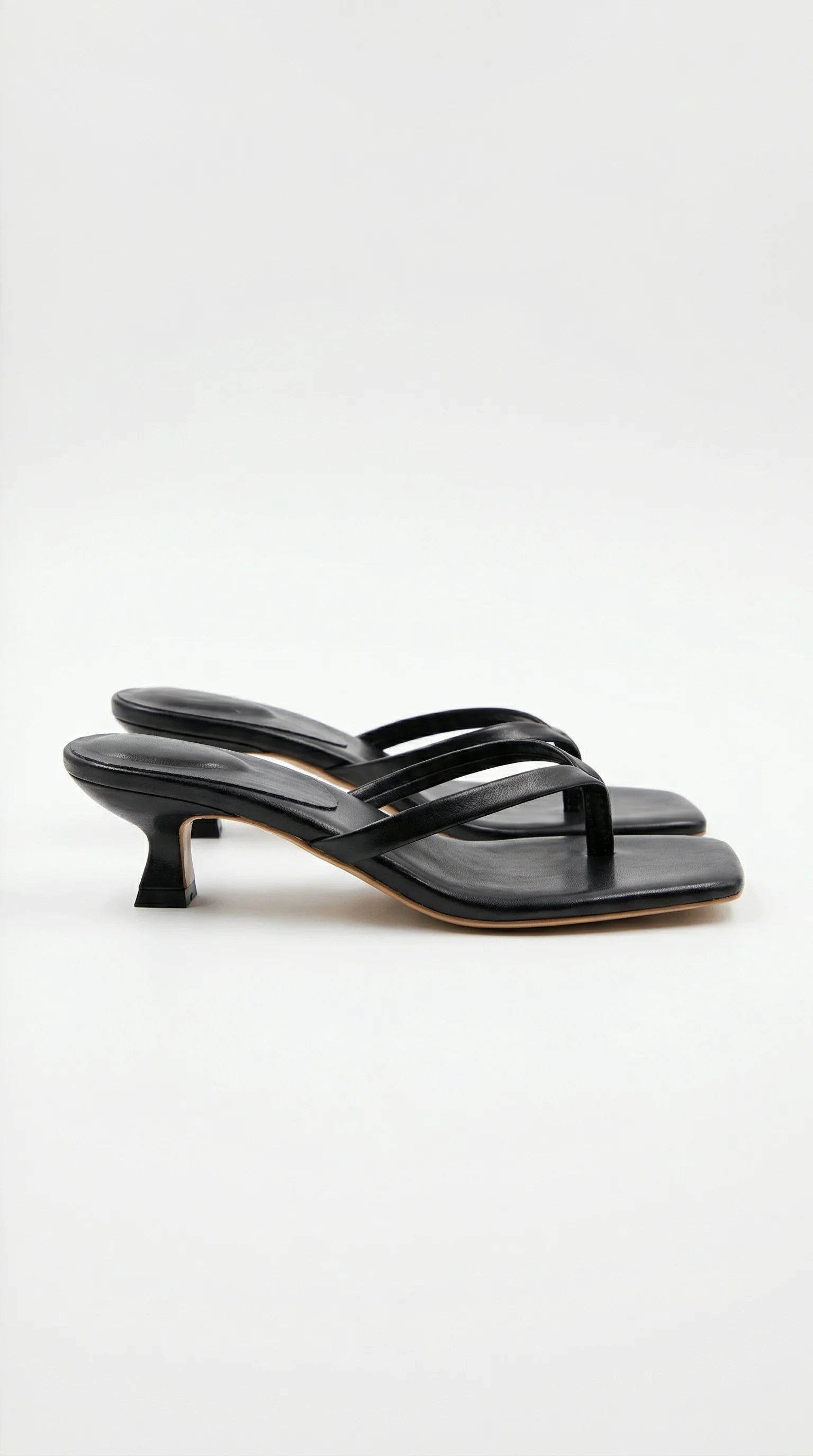 Dames kitten heel slippers met gekruiste bandjes en open teen in zijaanzicht op neutrale achtergrond
