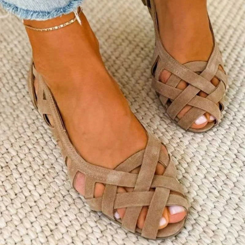 Dames gevlochten sandalen met platte zool en kruisende bandjes in taupe kleur gedragen op voeten