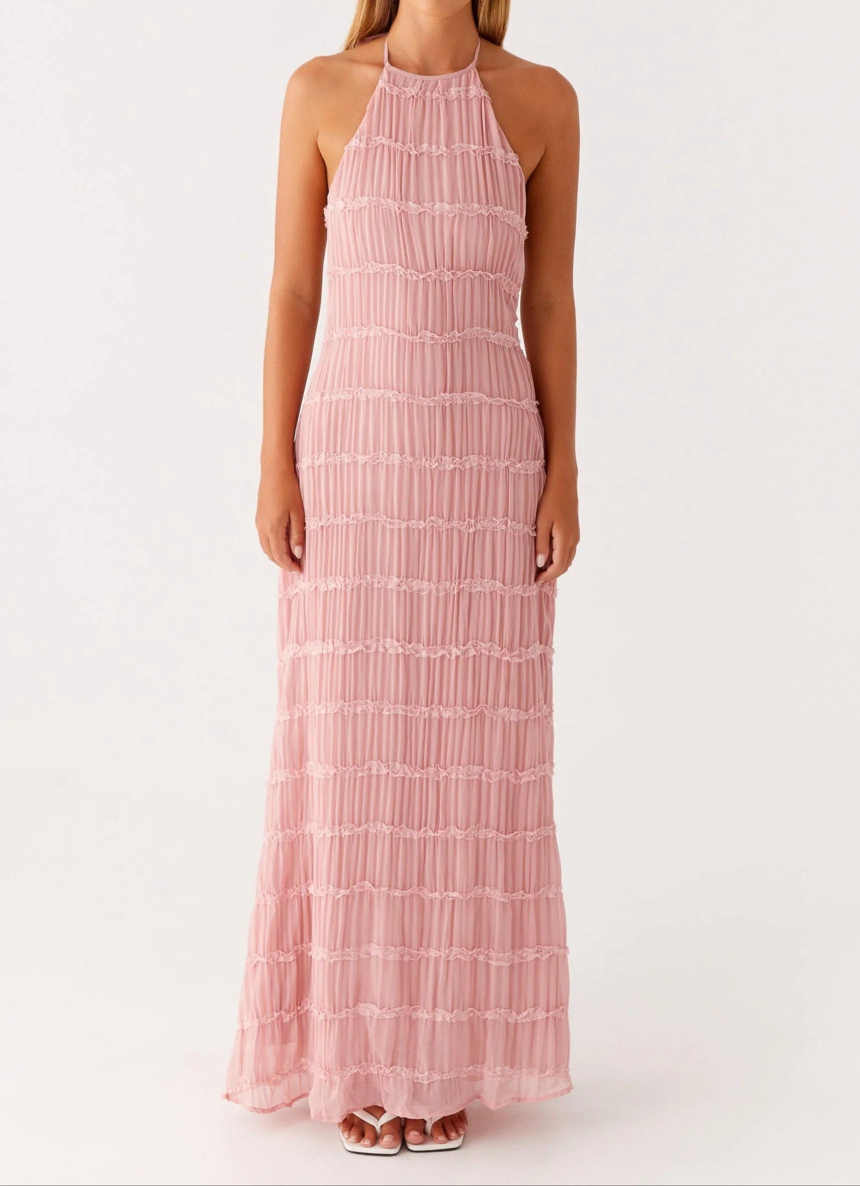 Vrouw in beweging met witte halter maxi jurk die moeiteloos meezweeft