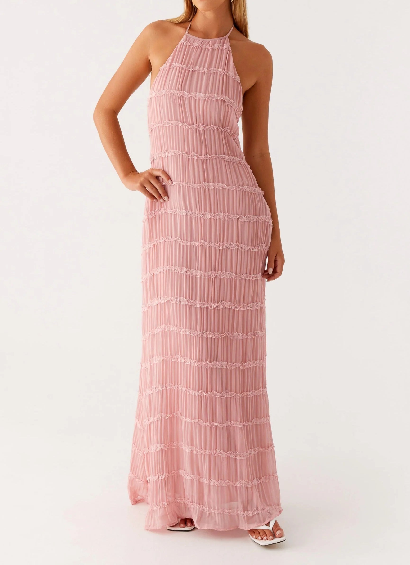 Vrouw draagt witte halter maxi jurk met minimalistische sandalen voor zomerse feesten