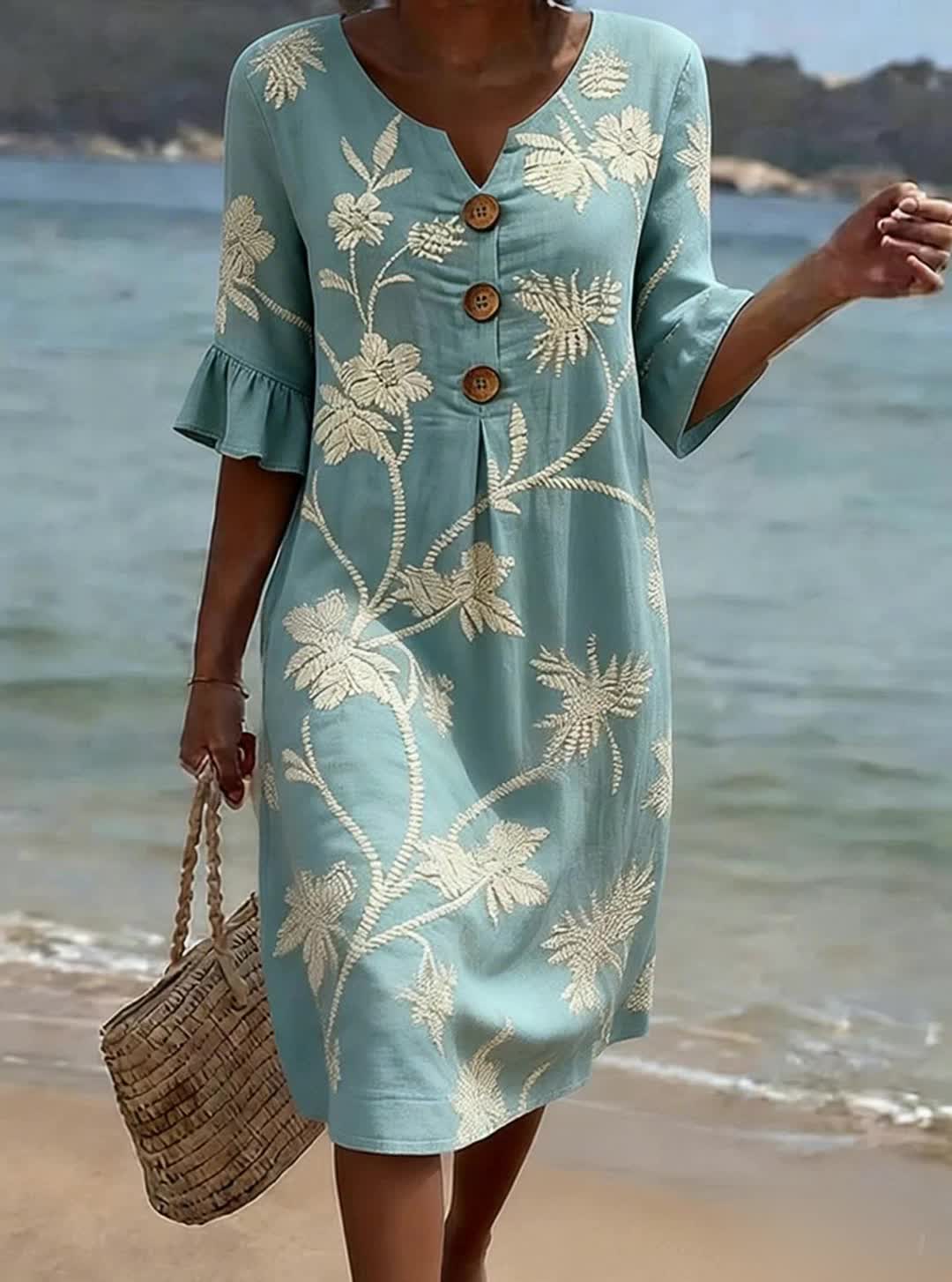 Vrouwelijke midi jurk met botanische print, losse pasvorm en decoratieve houten knopen aan de voorkant