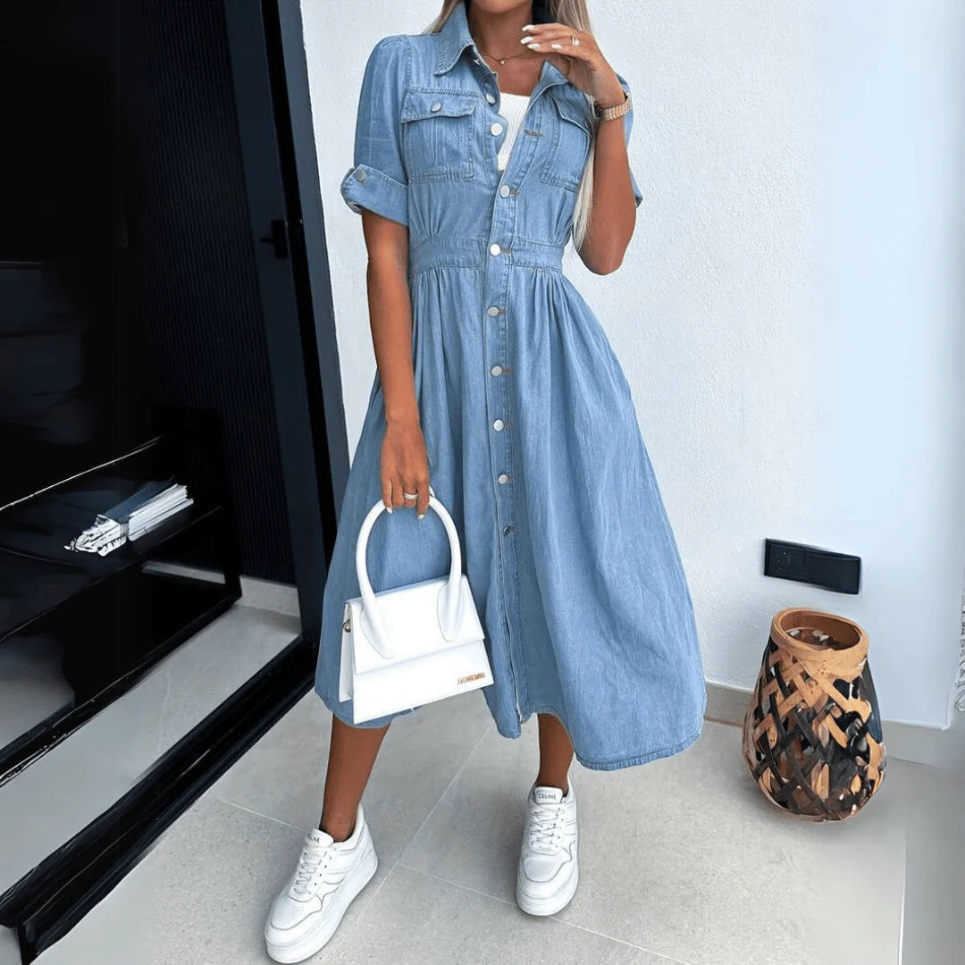 Zijaanzicht van denim midi jurk met kraag en borstzakken, gestyled met witte handtas voor dagelijkse outfit