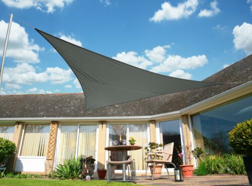 Beige rechthoekig schaduwdoek geïnstalleerd boven terras met tuinset en planten voor decoratieve schaduw