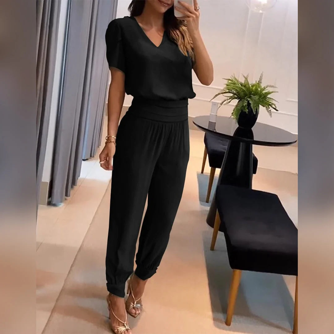 Zijaanzicht van zwarte dames jumpsuit met V-hals, korte mouwen en elastische enkelmanchetten