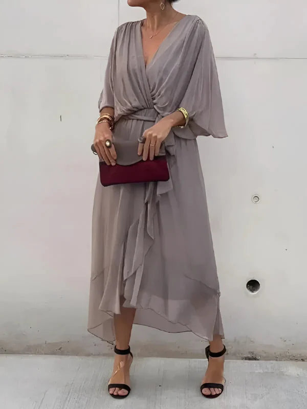 Vrouw draagt midi jurk met gouden accessoires en sandalen