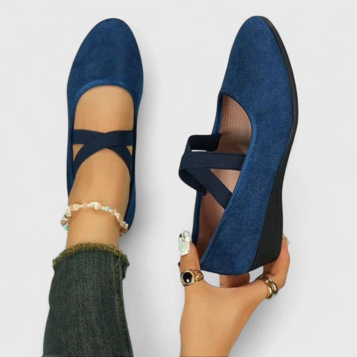 Zwarte ballerina's met elastische kruisbandjes over de voet, gedragen met spijkerbroek en gouden armband