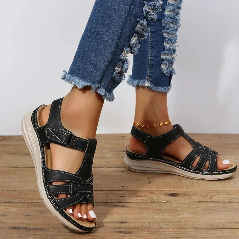Close-up van bruine leren sandalen met klittenbandsluiting en contrasterende stiksels