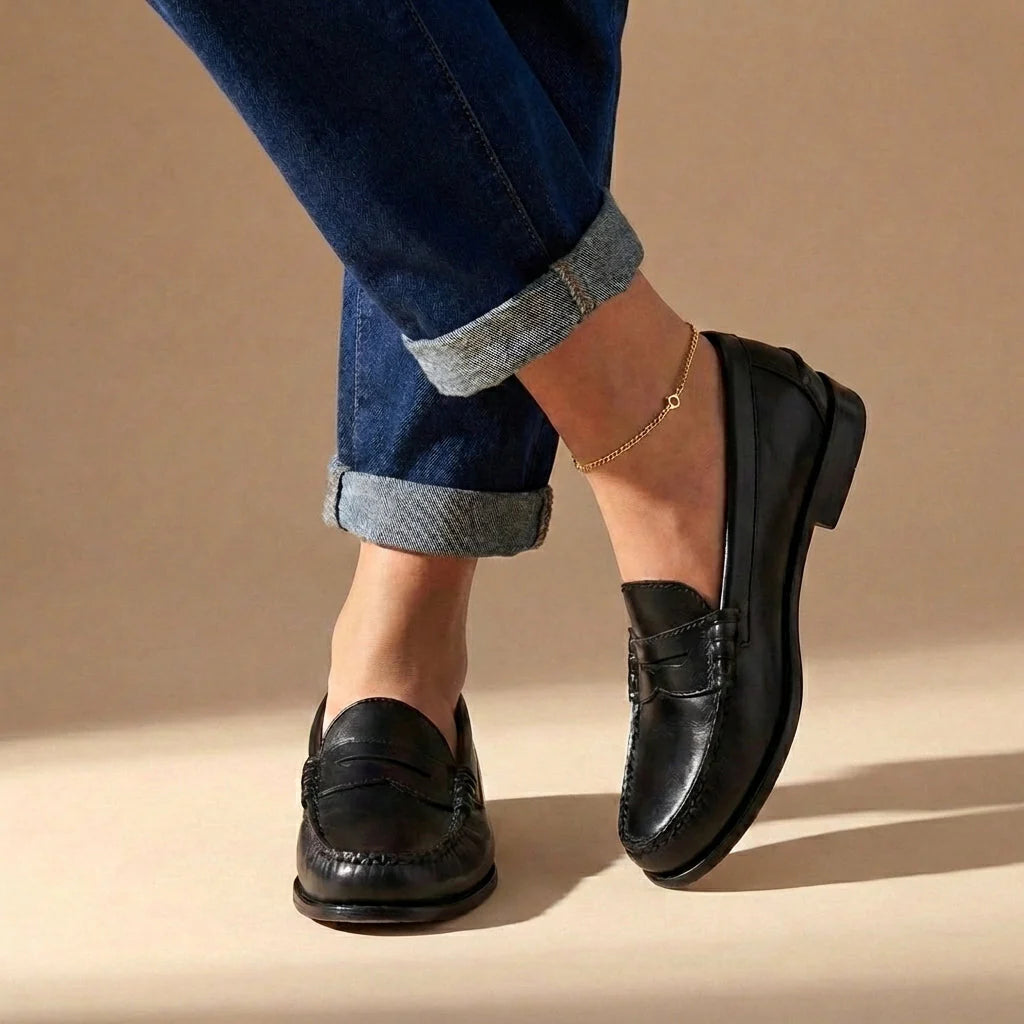 Zijaanzicht van dames penny loafers met zichtbaar stikwerk en decoratieve band over de wreef
