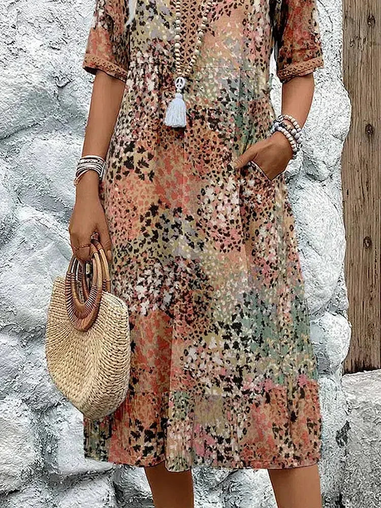 Zomerjurk met bloemenprint gedragen met rieten tas en accessoires, ideaal voor strandwandelingen en terrasbezoek