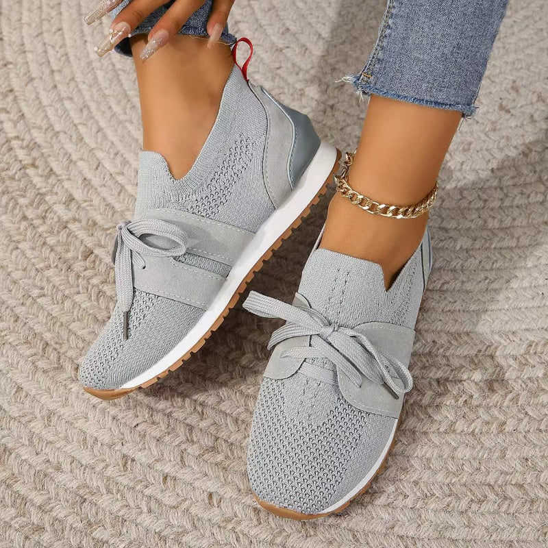 Zijaanzicht van zwarte gebreide sneakers met ondersteunende witte zool en contrasterende details