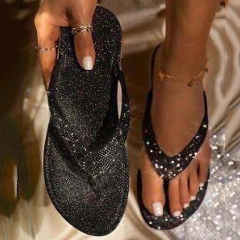 Dames teenslippers met strass-details in zwart, close-up van glinsterende bovenzijde en platte zool
