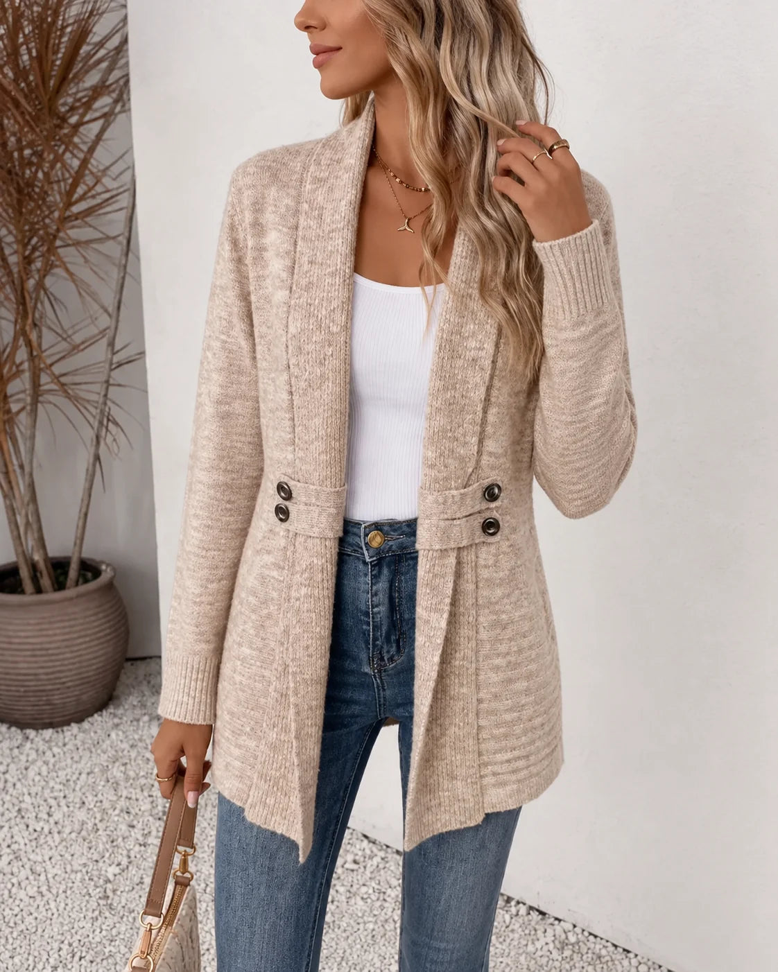 Vrouw draagt beige langvallend dames gebreid vest met open voorkant en knoopdetails aan de taille