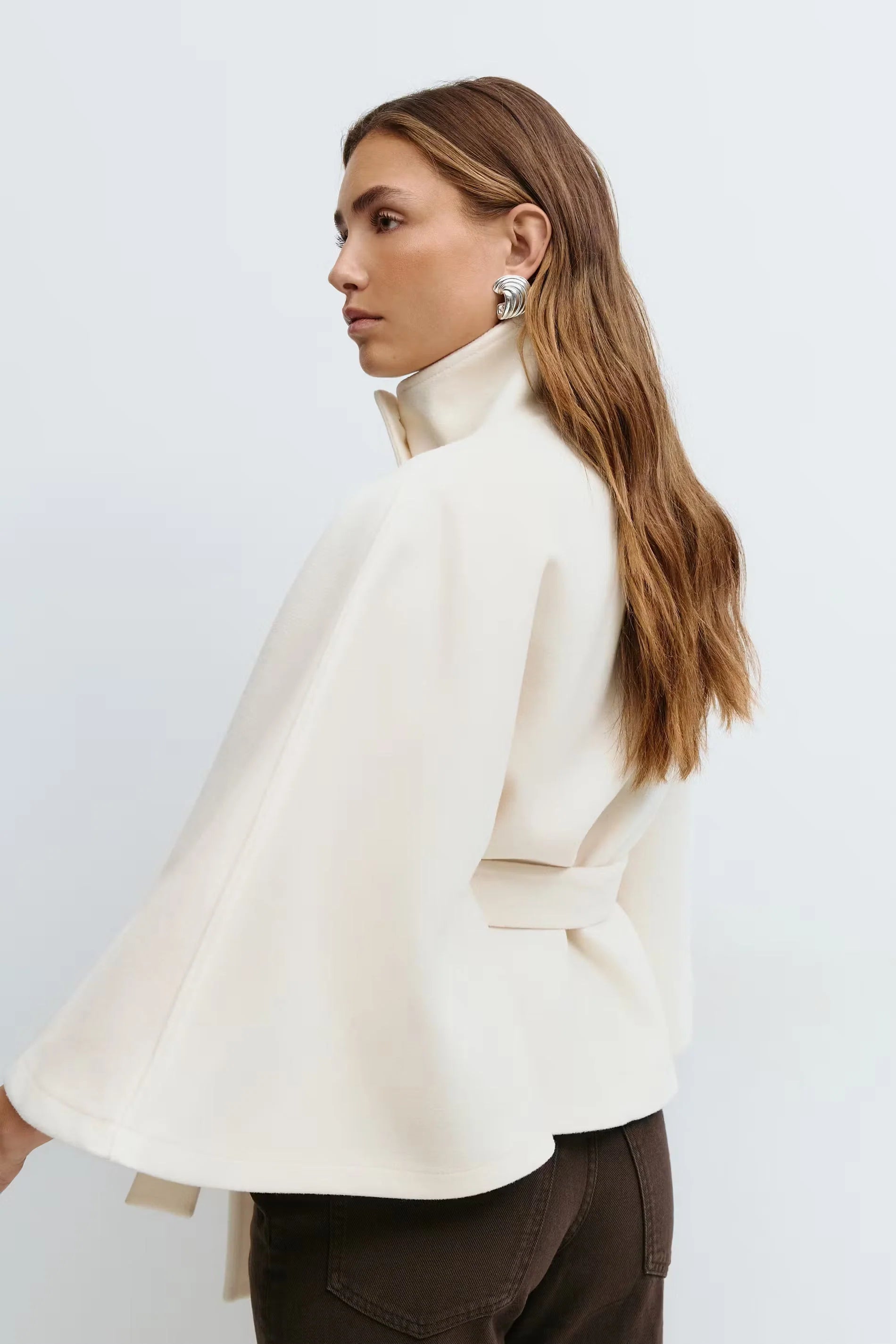 Detailopname van hoge kraag en knoopsluiting op beige dames trenchcoat met wijde mouwen