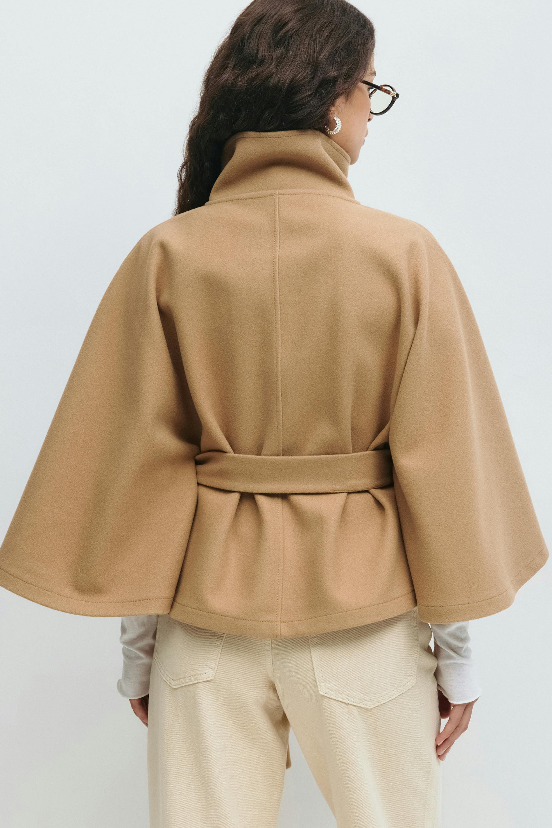 Detailopname van mouwen en ceintuur op beige korte trenchcoat voor dames