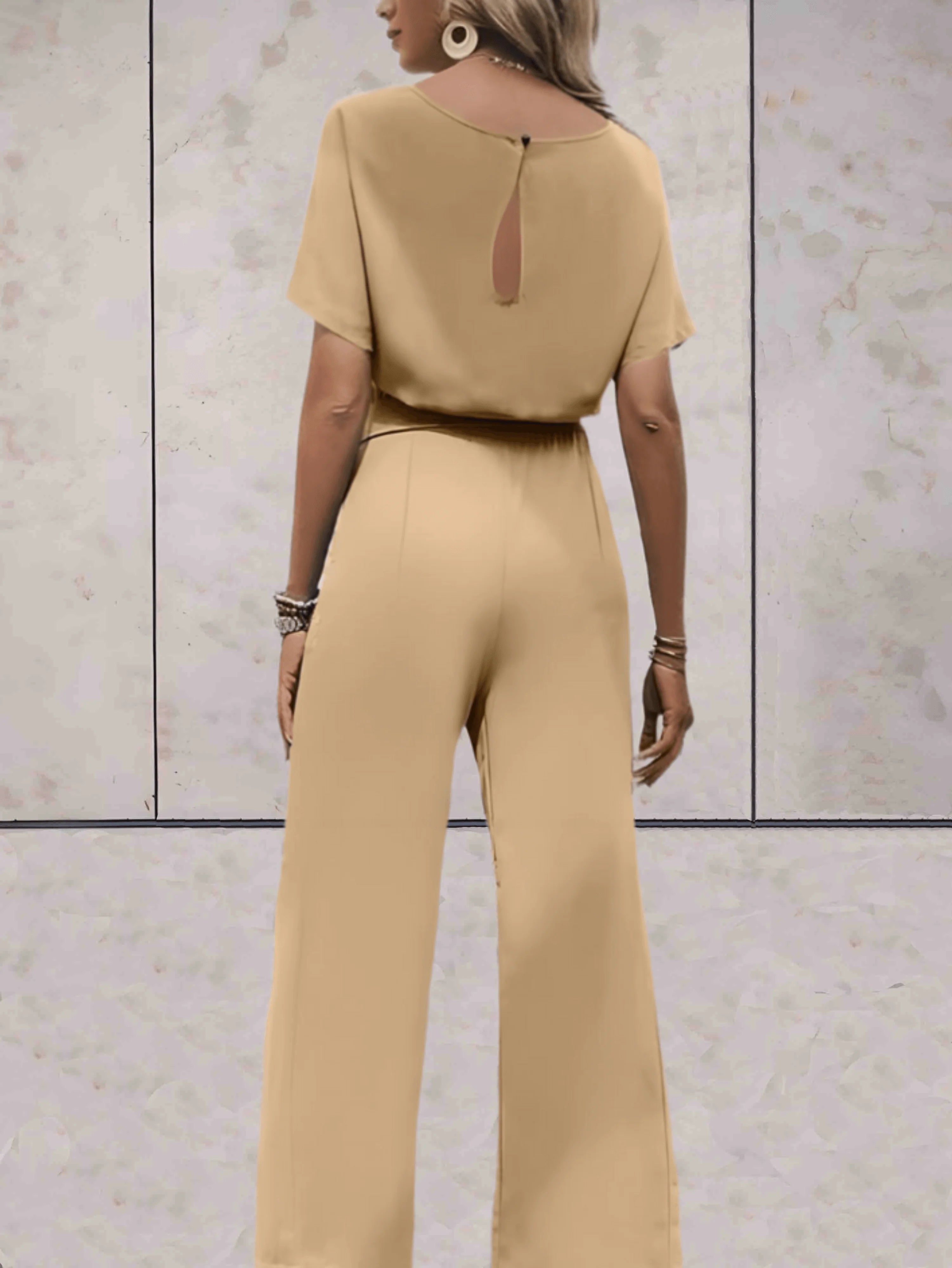 Model draagt zwarte jumpsuit met armbanden en casual styling