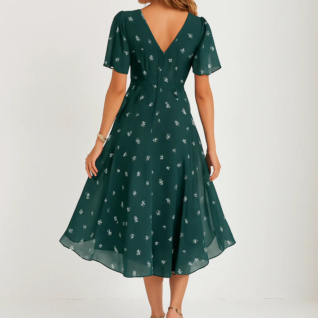Detail van bloemenjurk midi met delicaat wit bloemenpatroon op groene chiffon stof