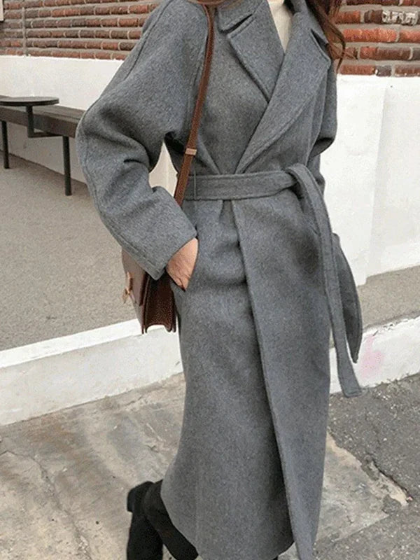Lange wollen damesjas gedragen met zwarte coltrui en schoudertas voor casual-chique look