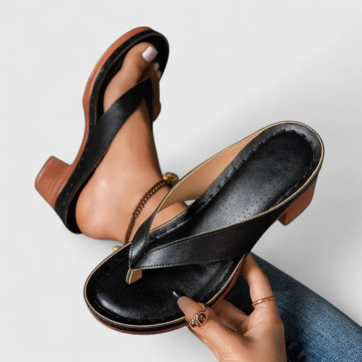 Close-up van dames teenslippers met brede chunky hak en diagonale bandjes in zwart