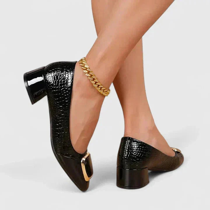 Detail van gouden gespdetail op bruine dames pumps met croco reliëf patroon