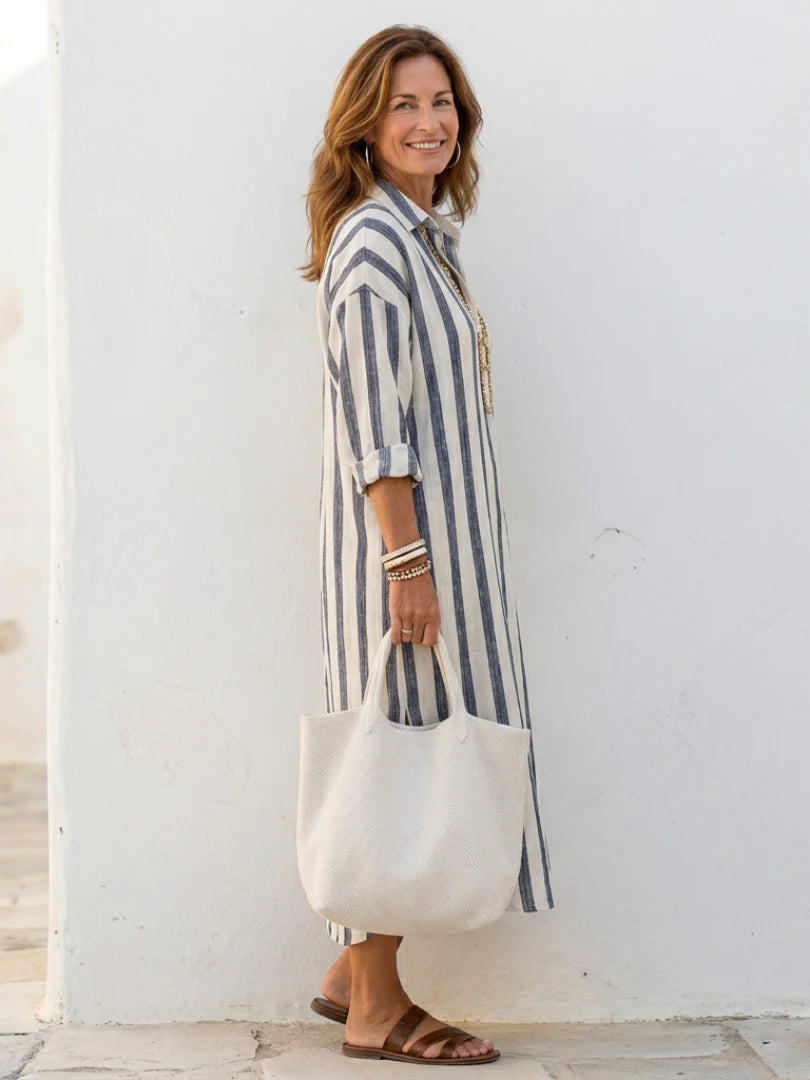 Detail van gestreepte midi shirtjurk met verticale blauwe en witte strepen en knoopsluiting