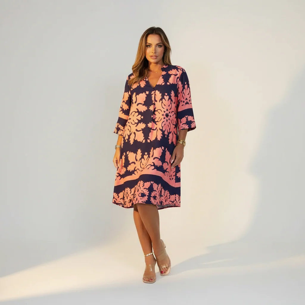 Model draagt de midi jurk met V-hals gecombineerd met neutrale accessoires