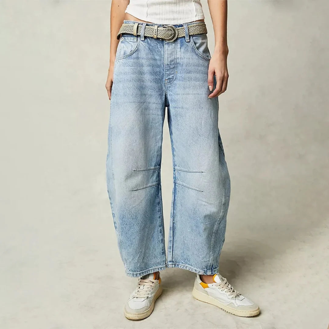 Dames barrel jeans met lichte wassing en wijde pijpen, gedragen met gevlochten riem en witte sneakers