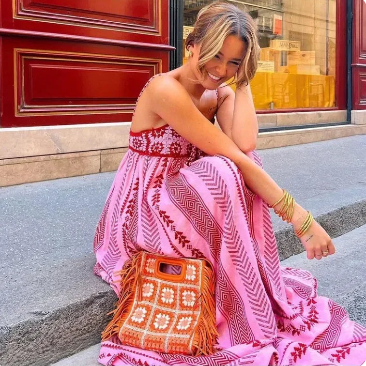 Close-up van maxi zomerjurk met empire taille en verfijnde bandjes in roze tinten