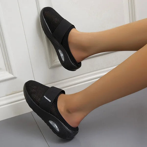 Dames orthopedische slip-on sandalen in zwart met gebreide mesh en ondersteunende zool gedragen aan voeten