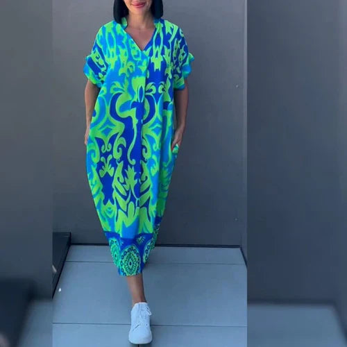 Vrouw draagt kaftan midi jurk met grafisch blauw-groen print en V-hals in losse pasvorm