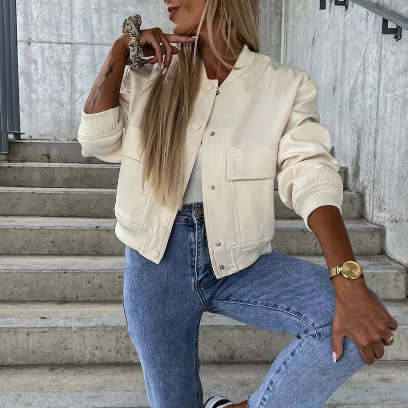 Close-up van beige bomber jas met drukknopen en opgestikte zakken met klep