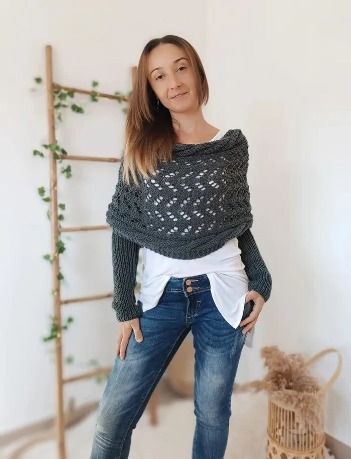 Vrouw draagt grijze gebreide bolero met mouwen in relaxte pose tegen witte achtergrond
