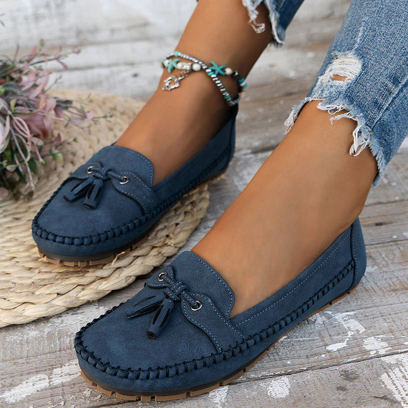 Dames loafers met strikaccent en mocassinrand gedragen met gescheurde jeans op houten ondergrond