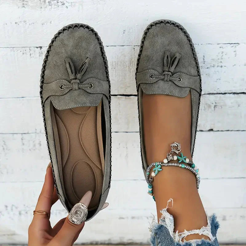 Detail van strikaccent met metalen oogjes op dames loafers