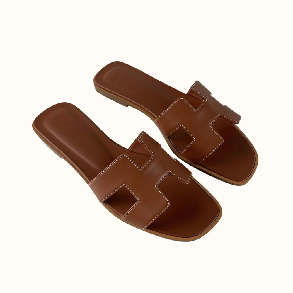 Close-up van H-design detail op leren instap sandalen voor dames in witte kleur