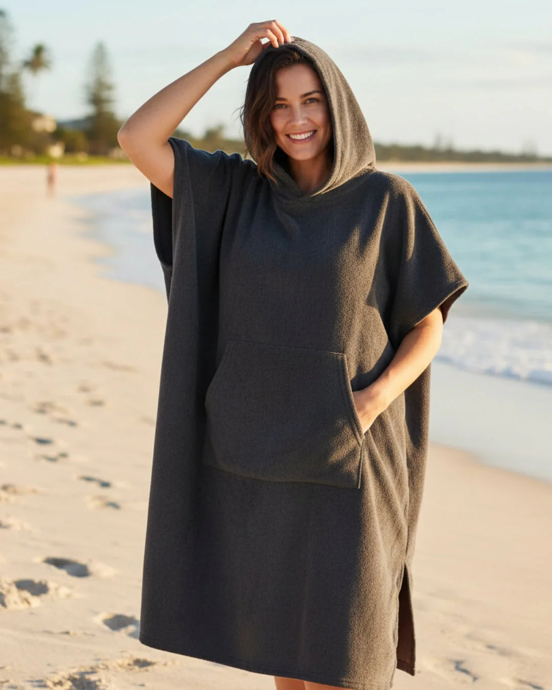 Model toont draagcomfort van poncho jurk met capuchon bij het water