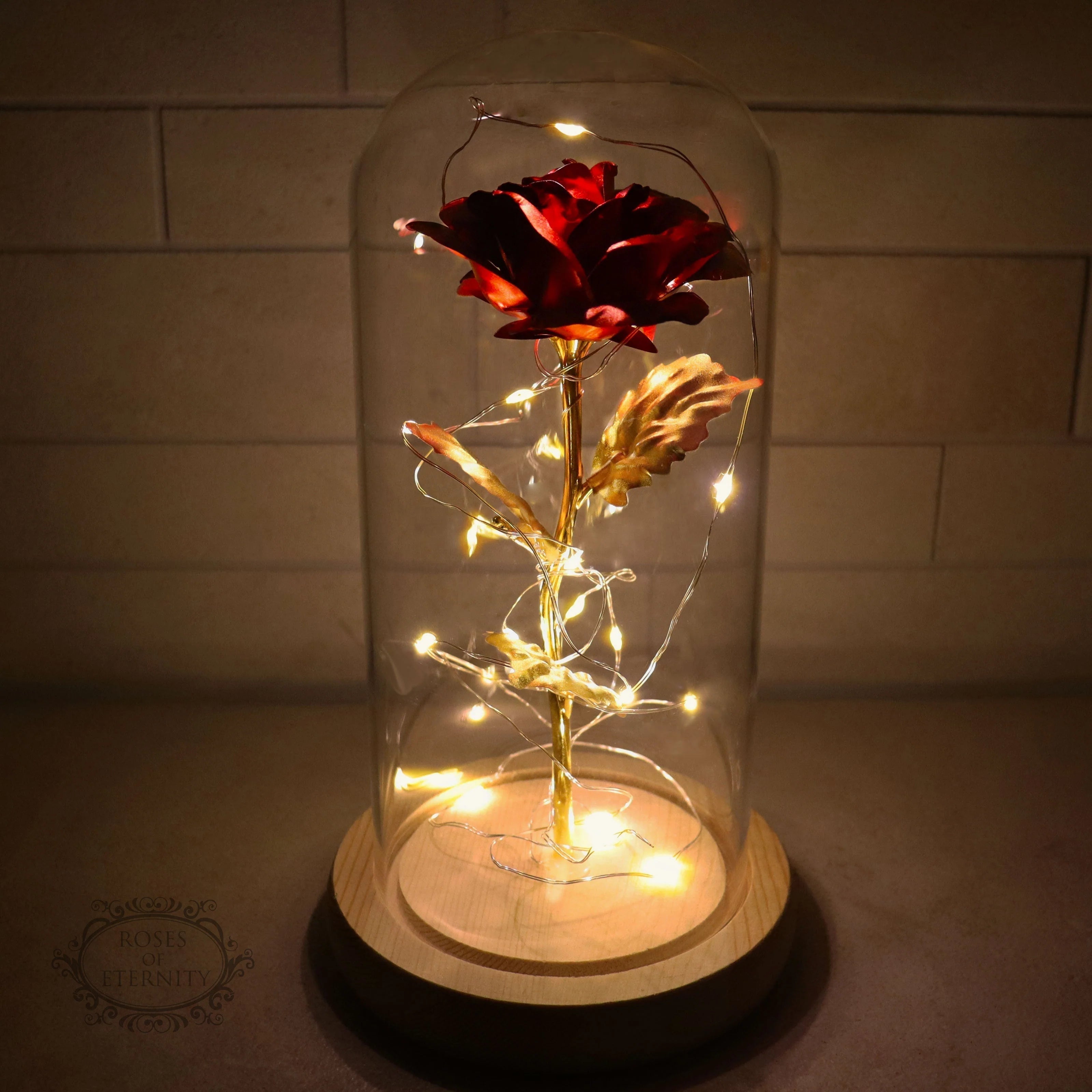 Gouden roos onder glazen stolp met LED-verlichting voor romantische sfeer