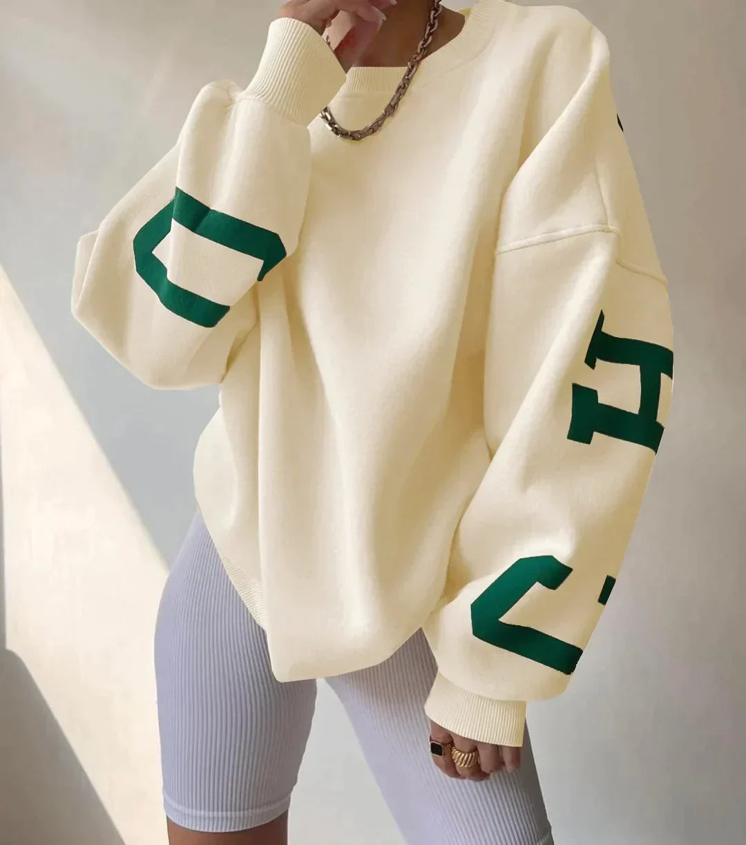 Detail van grafische witte strepen op de mouwen van groene dames sweatshirt