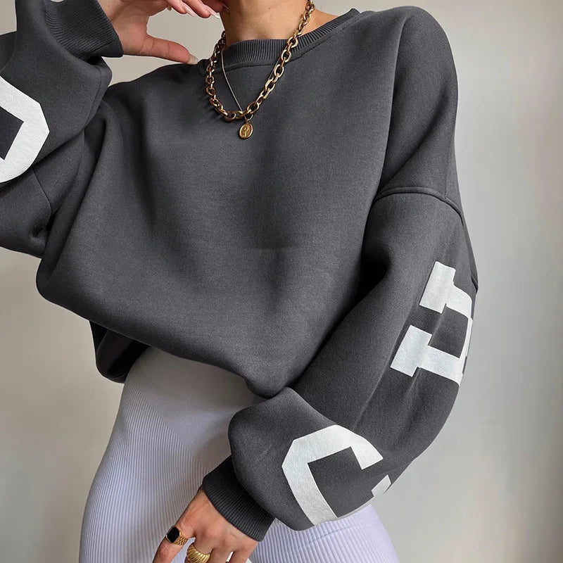 Close-up van geribbelde manchetten en grafische mouwtekening op groene dames sweatshirt