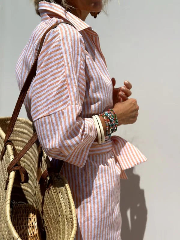 Gestreepte blousejurk gedragen met sandalen en accessoires voor zomerse look